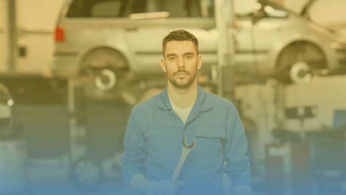 technician standing in shop holding a wrench