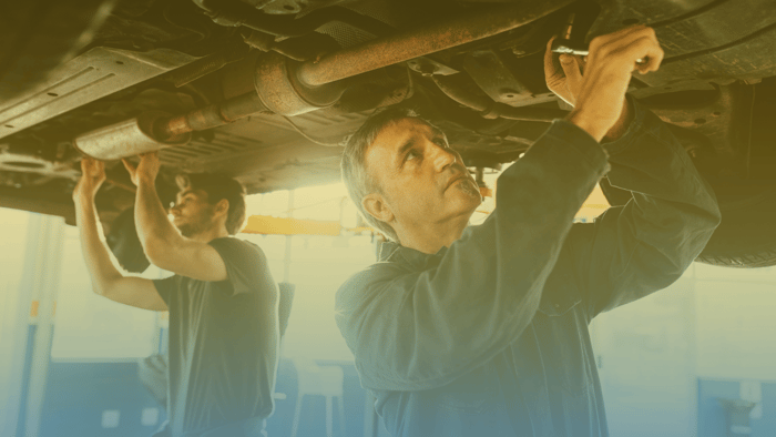 two technicians working under a car on a lift